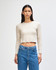 A fitted, long-sleeved crop t-shirt in a light beige colour, paired with high-waisted blue jeans.