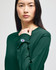 An olive green long-sleeve t-shirt featuring a small logo on the sleeve, modelled by a woman.