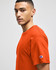 An orange Champion adult jersey short sleeve t-shirt displayed on a model. The shirt features a logo on the sleeve.