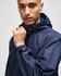 A navy full-zip anorak jacket with a hood, featuring an emblem on the sleeve.