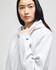 A grey full-zip hooded sweatshirt with a logo on the sleeve, featuring a model wearing it.