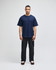 A navy t-shirt with short sleeves on a male model, paired with black pants. The shirt features a logo.