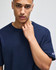 A navy blue Champion Adult Heritage Jersey T-Shirt featuring a logo on the sleeve, held by a model.