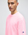 A pink Champion Adult Heritage Jersey T-Shirt displayed on a model, featuring a logo on the sleeve.