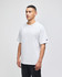 A white Champion adult heritage jersey t-shirt on a model, featuring a logo on one sleeve.