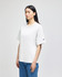 A white Champion adult heritage jersey t-shirt on a model, featuring a logo on one sleeve.