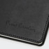 A black diary with a textured cover and embossed branding, featuring white stitching along the edges.