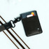 A black vertical wallet with a textured front, featuring a card slot and an attached clip for easy attachment.