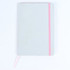 A grey notebook with a pink elastic band and a ribbon bookmark, featuring a dotted texture on the cover.