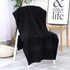 A black bath towel draped over a chair, showcasing its plush fabric and elegant design. There’s a decorative sign in the background.