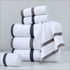 A stack of white bath towels with grey stripes, featuring both rolled and folded towels. Includes a towel with a corner draped.