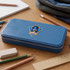 A blue pencil case with a logo sits on a wooden desk surrounded by pencils, an eraser, a ruler, and a notebook.