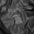 A black windbreaker made of 100% polyester, featuring care instructions and a logo.