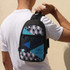 A crossbody bag featuring a geometric pattern in black, turquoise, and blue, held by a person. It has a logo.