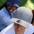 A grey cap with a textured surface and a logo, worn by a person, alongside a person in a navy cap.