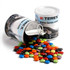 A branded can containing colourful choc beans, some spilling out onto a surface.