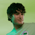 A young man with dark, wavy hair wears black earbuds against a green background. The product features a logo.