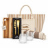 A tote bag with stripes, a wooden cheese board, a two-piece cheese set, two textured glasses, and a striped blanket.