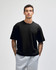 A black heavyweight cotton unisex boxy t-shirt worn by a model, paired with grey sweatpants.