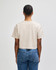 A heavyweight cotton women's crop t-shirt in beige, featuring a boxy fit and branding on the back.
