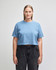 A blue cropped boxy t-shirt made from heavyweight cotton, featuring a logo on the fabric.