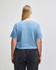 A blue crop boxy t-shirt with a back view, featuring a relaxed fit and short sleeves. There is a logo present.