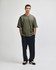 A model wears an olive-green oversized boxy top with light green cargo pants and white sneakers.