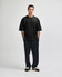 A black oversized boxy top worn with blue denim jeans, featuring a casual, relaxed fit and a logo.