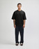 A black oversized boxy top with a crew neckline, featured on a model with short blonde hair.