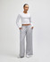 A pair of grey wide leg pants displayed with a model wearing a white long-sleeve top. The pants feature pockets and a drawstring.