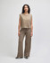 Wide leg pants in a beige colour, worn by a model with a white tank top. The pants feature a drawstring waist and have a logo.
