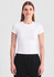 A white baby tee with short sleeves, paired with black trousers. The model stands against a neutral background.