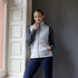 A light grey women's hybrid vest with a zip closure, styled with a grey long-sleeve top and navy pants, featuring a logo.