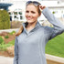 A grey women's quarter zip jumper with a collar and a logo. The model is wearing sunglasses.