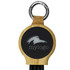 A round, black and bamboo keychain featuring a keyring attachment and a logo on the front.