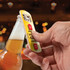 A drink bottle opener with a metallic finish and a yellow handle, held above a beer bottle.