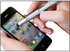 A stylus pen in silver is being used on a smartphone screen, displaying various app icons.