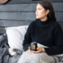 A black Zen mirror finish mug with a logo, held by a woman sitting on a couch with a blanket.