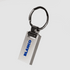 A silver metal keychain with a sleek rectangular design and a circular attachment ring. It has a branding logo.