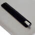 A metal pen with a silver tip, resting in a black leather holder on a grey surface. The image features branding.