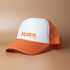 A Trucker Roadhouse Cap featuring an orange brim and mesh back with a white front panel and logo.