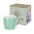 A mint green coffee mug beside a decorative box featuring floral designs and a logo.