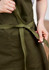 An olive green apron with a tied waist strap, featuring pockets and a textured fabric.