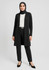 A longline cardigan in black, paired with a white blouse and black trousers, worn by a woman in a hijab.