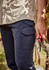 Men's lightweight outdoor cargo pants in navy blue, featuring side pockets and a logo. A hand holds pruning shears.