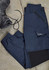 A pair of navy women's work pants laid flat, featuring pockets and an elastic waistband, beside a work boot.