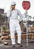 A man in a white work jumpsuit stands on a construction site holding a stop sign, wearing a helmet and gloves.