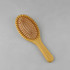 A bamboo hair brush with a rounded shape and wooden bristles on a natural wood base.
