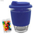 A dark blue coffee cup with a silicone sleeve, accompanied by a packet of assorted jelly beans.