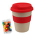 A bamboo cup with a red silicone lid and band, accompanied by a packet of colourful jelly beans.